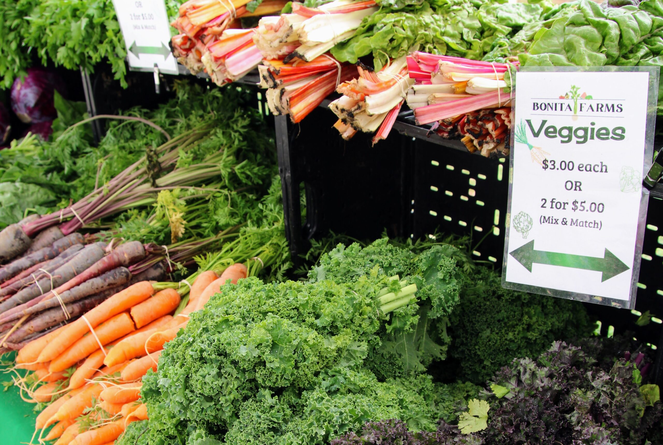 Kale, carrots, and rainbow chard bunches at the market