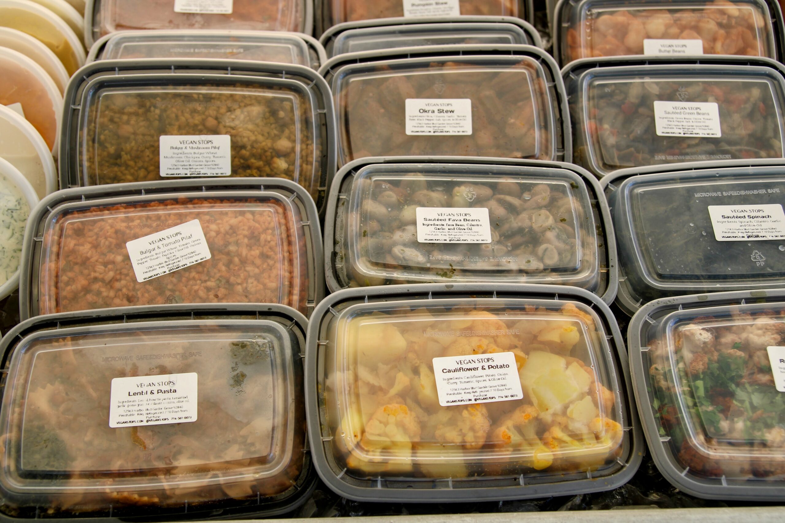 Prepared vegan meals in stacked containers at a farmers market