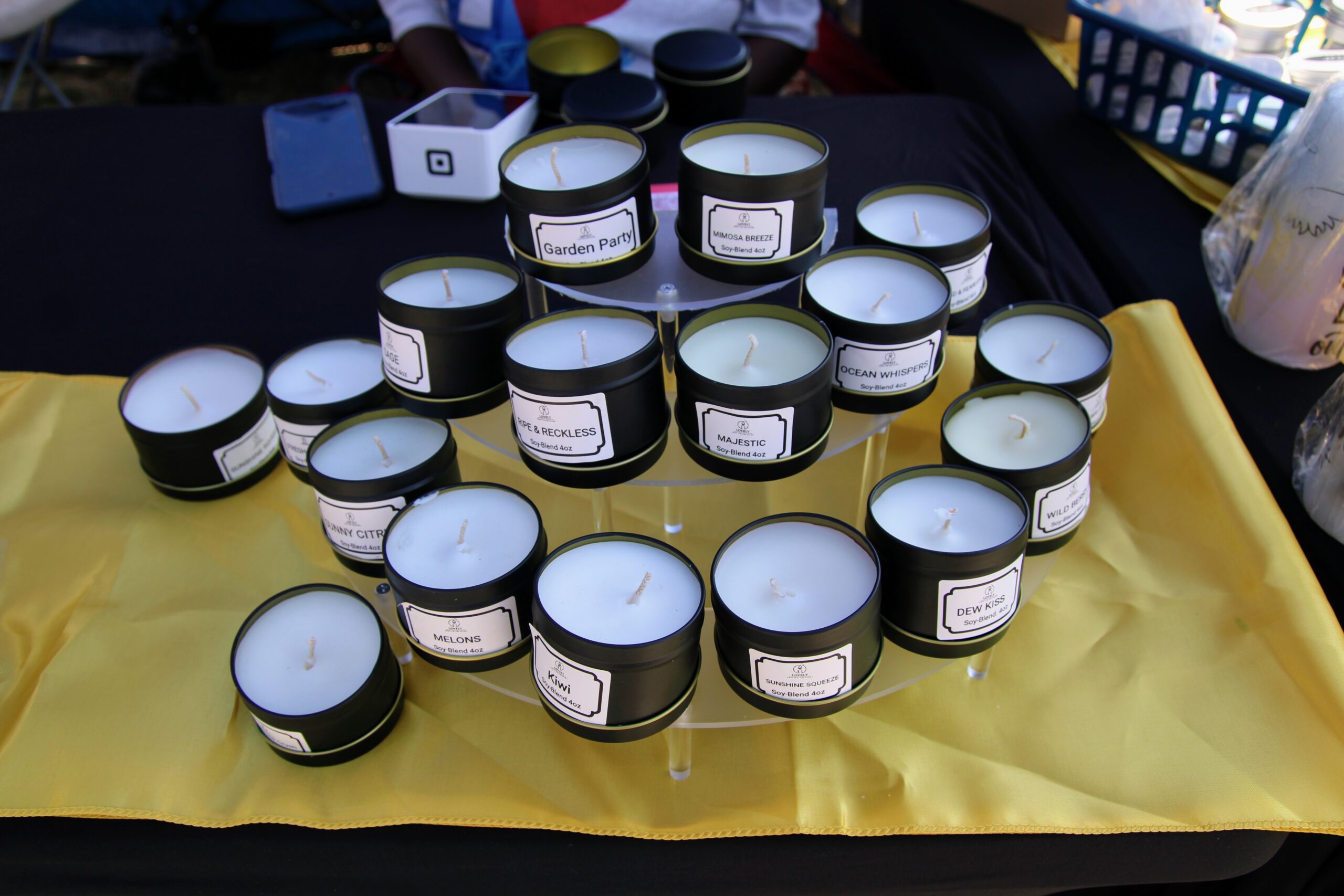Soy candles in black tins on a yellow tablecloth