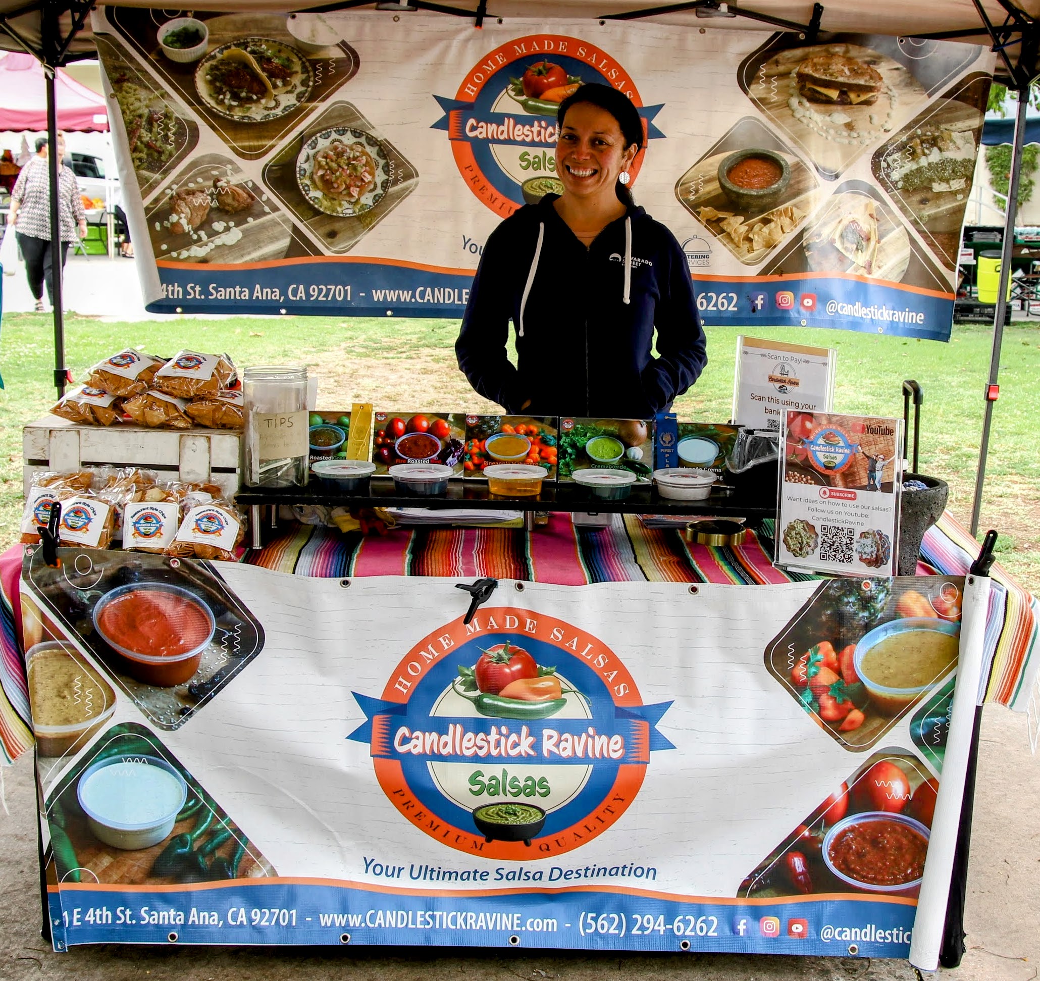 Smiling salsa vendor at a Local Harvest Farmers Market stand