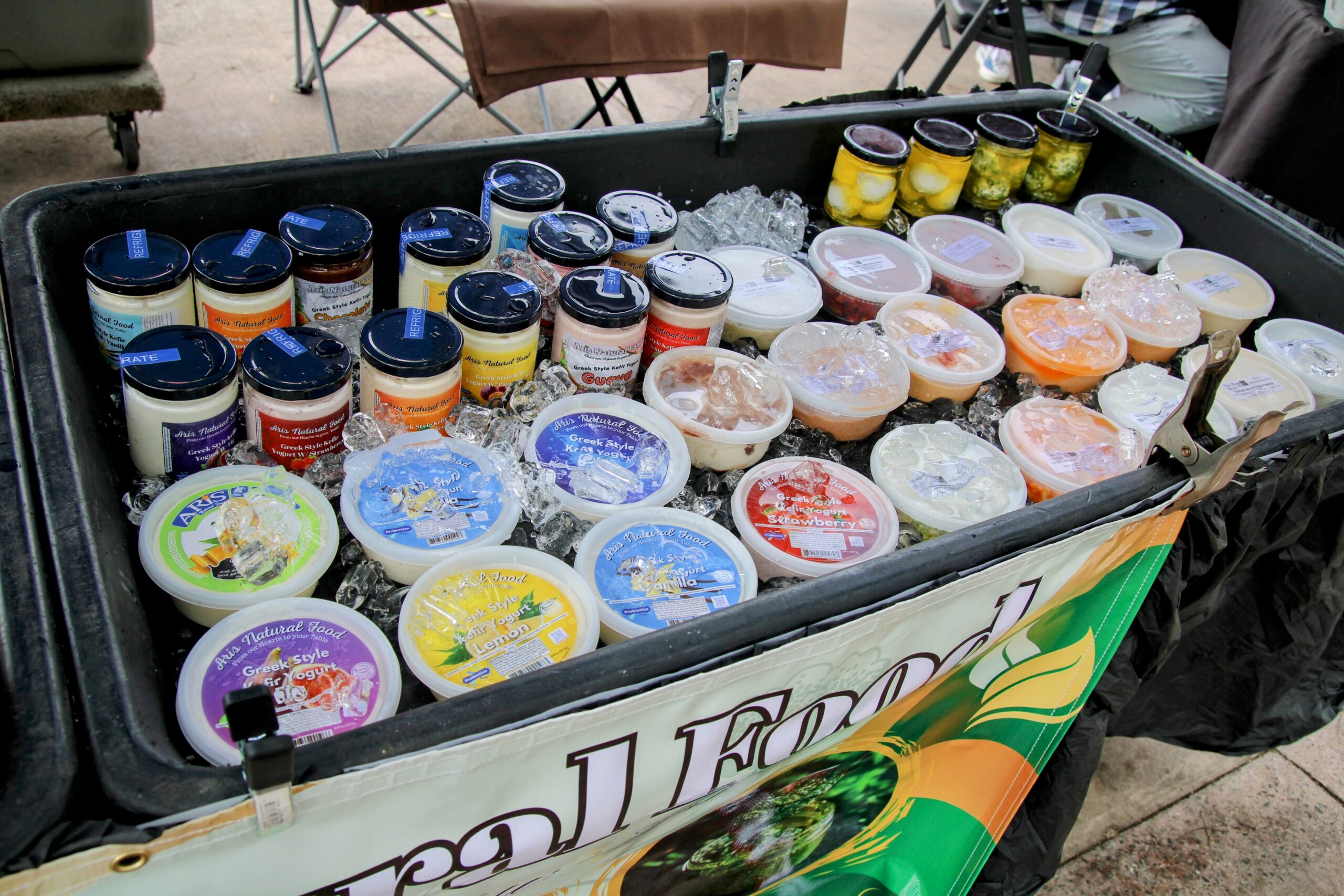 Yogurt tubs and jars packed on ice at a farmers market