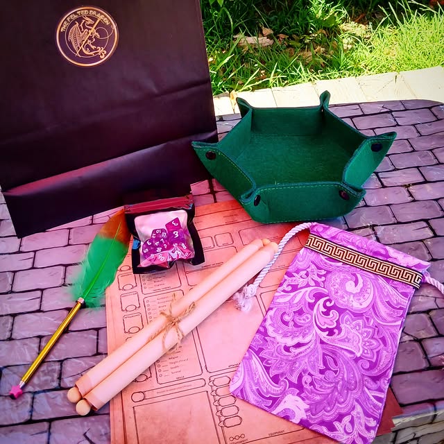 Green dice tray, purple patterned velvet bag, polyhedral dice, scrolls, and a feather quill on a game mat.