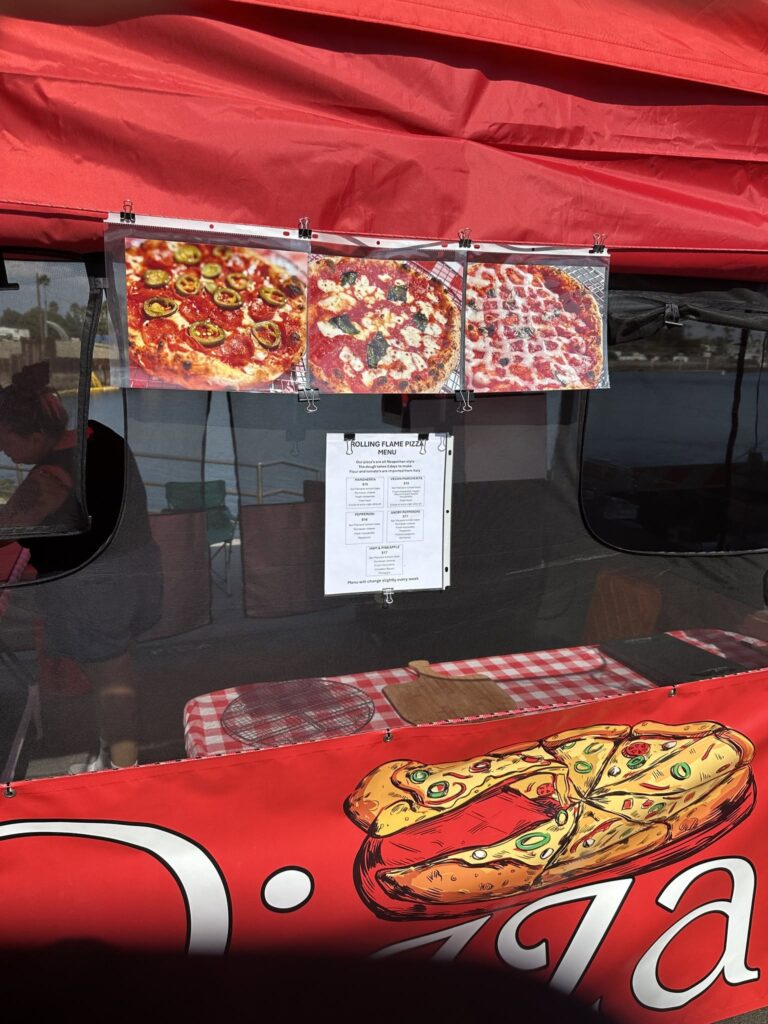 Red market tent with three printed pizza photos and a menu clipped to the front